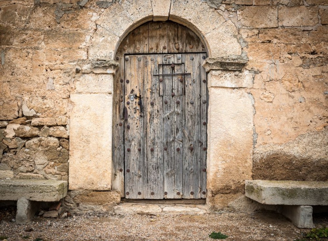 Image de Ancient wooden door on a stone made wall and cement benches
