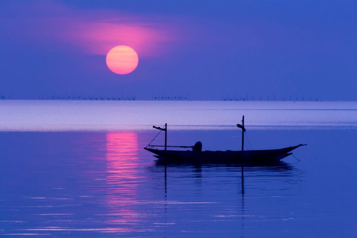 Picture of Peaceful Morning at sunrise with small boat silhouette in the beach
