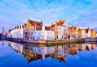 Afbeeldingen van Cityscape view of Bruges and traditional houses reflected in water at sunrise in Belgium