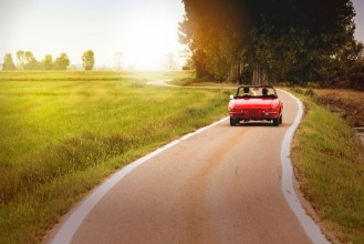 Picture of Classic red convertible car traveling in the countryside at sunset