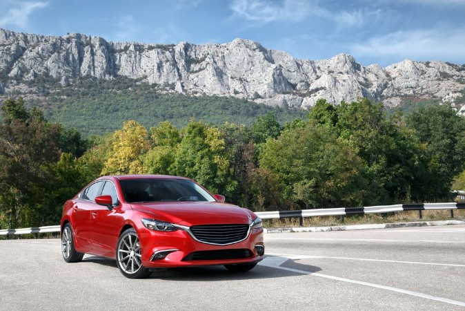 Afbeeldingen van Red car standing on the road near mountains at daytime