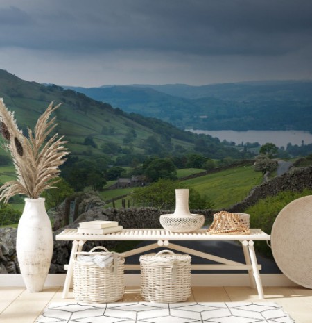 Afbeeldingen van Lake District England - May 30 2012 Rural road with stone walls on the side meanders through the landscape Shot from above shows lake downhill Green meadows forests and ferns