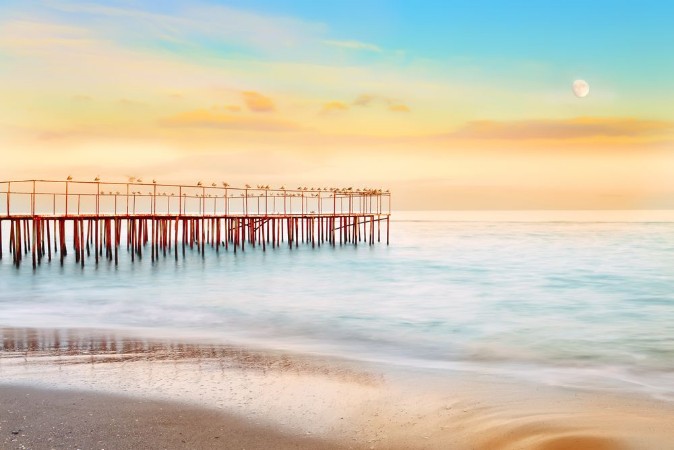 Picture of Wonderful evening by the sea Long exposure blurred water waves dashing on the shore the old pier with seagulls soft focus