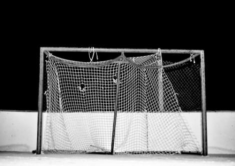 Picture of Close-up of tattered and frayed mesh on a hockey net on an outdoor ice skating rink at night in black and white