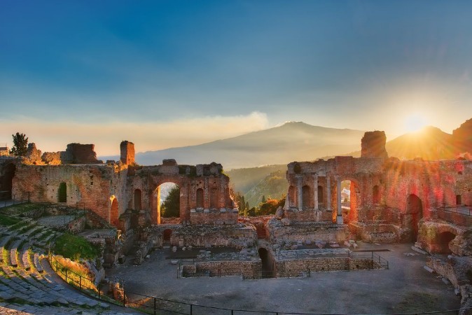 Obrázek Particular of Ancient theatre of Taormina with Etna erupting volcano at sunset