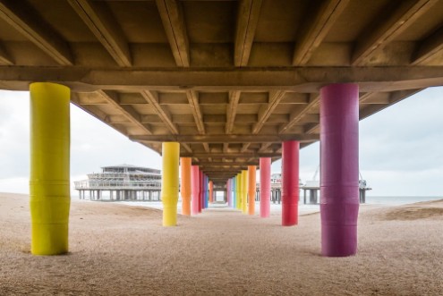Bild von Shot under pier with color painted columns on the beach at sunset
