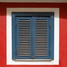 Afbeeldingen van A beautiful old window on a red wall with closed blue shutters The window is photographed in the old town in Riga