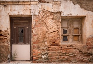 Bild på Ancient wooden door and a window on a wall made of bricks