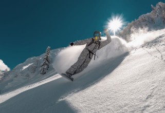 Ritratt ta’ Snowboarder rides in cloud of powder snow
