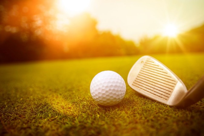 Afbeeldingen van Golfplatz im Abendrot mit Loch und Golfball und Fahne
