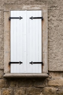 Picture of White narrow wooden closed window shutters with metal ornaments