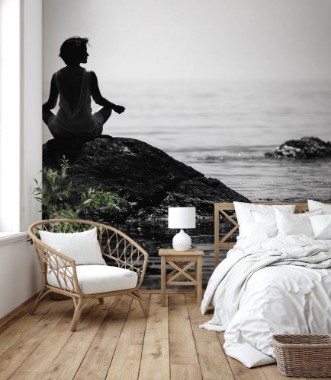 Image de Young woman sits in a lotus position on a large stone in the sea and meditates her fingers are folded in Prithivi mudra