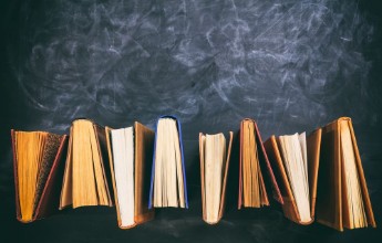 Afbeeldingen van Vintage books standing on blackboard background - top view