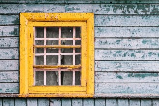 Afbeeldingen van Yellow window on green wooden wall of abandoned house