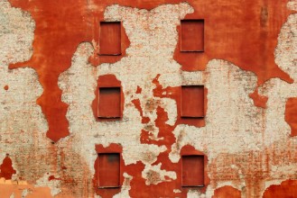 Picture of Boarded windows in old brick wall covered with red flaking plaster
