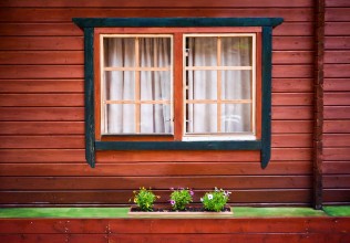 Afbeeldingen van Windows with curtains and some green flowers on painted wooden house
