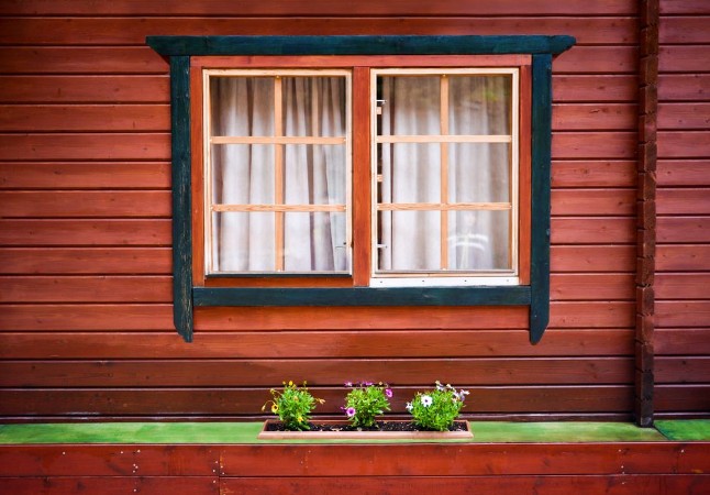 Εικόνα της Windows with curtains and some green flowers on painted wooden house