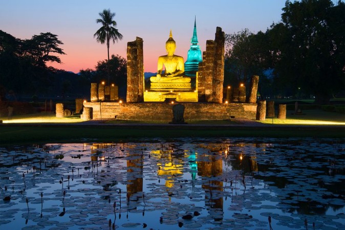 Image de Ancient sculpture of a sitting Buddha on the ruins of the temple of Wat Tra Phang Ngoen in the night illumination Sukhothai Park Thailand