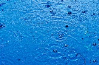 Afbeeldingen van Rain drops on the surface of a street road on a rainy day toned blue