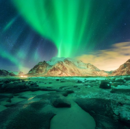 Afbeeldingen van Aurora over snowy mountains Northern lights in Lofoten islands Norway Starry sky with polar lights Night winter landscape with green aurora borealis stones sandy beach rocks illumination 