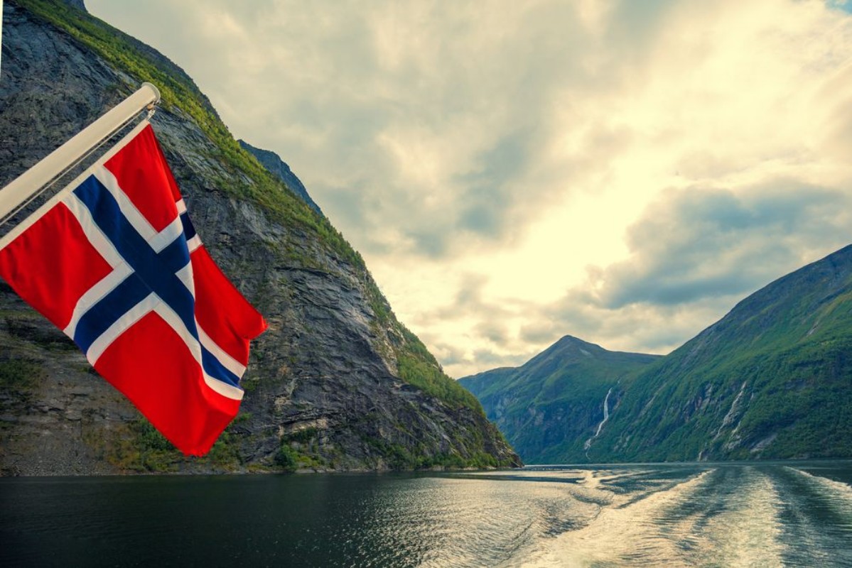 Picture of Mountain landscape with cloudy sky Majestic Geiranger fjord  View from ship Norvegian flag against beautiful nature of Norway