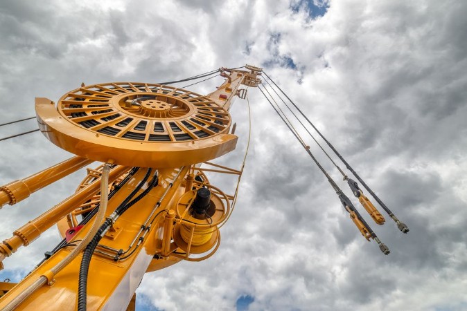 Image de The boom of a drilling machine and a crane against the sky