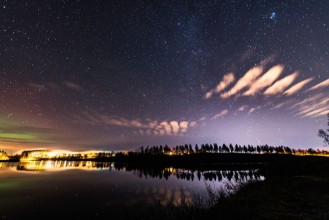 Image de Starting weak Aurora at almost clear skies tiny clouds like feathers above lake at Scandinavian countryside