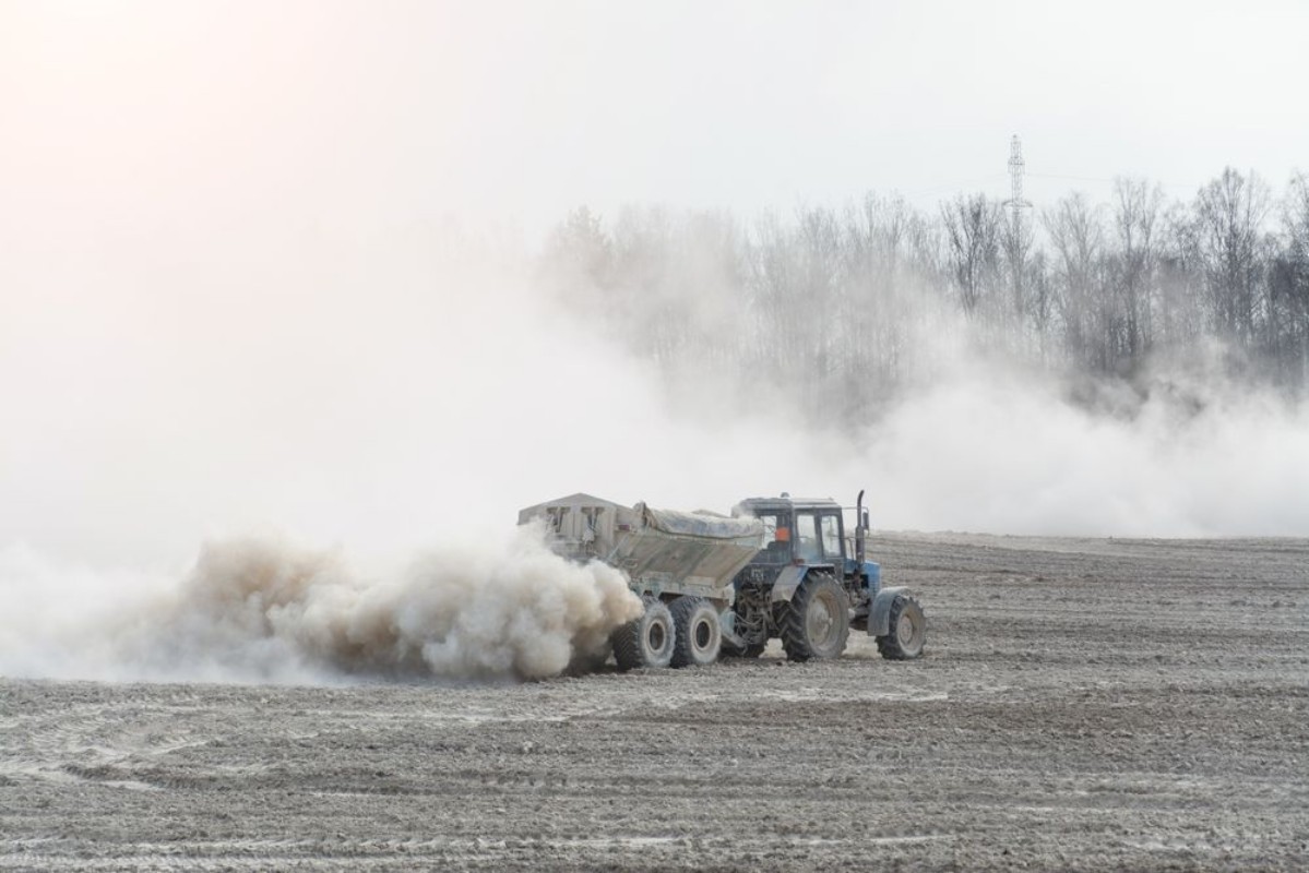 Afbeeldingen van Tractor with trailer fertilizes agricultural field in spring for sowing corn