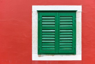 Picture of Single window with green shutters set in red wall in Skradin
