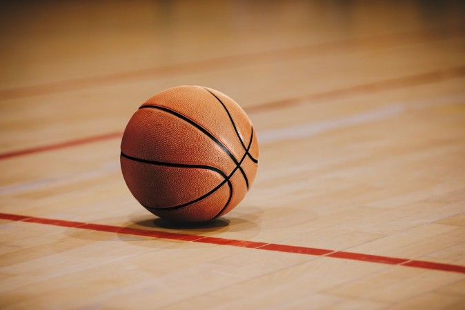 Afbeeldingen van Classic Basketball on Wooden Court Floor Close Up with Blurred Arena in Background Orange Ball on a Hardwood Basketball Court