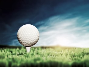 Picture of Golf ball placed on white golf tee on green grass golf course