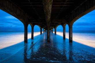 Afbeeldingen van Twilight dusk landscape of pier stretching out into sea with moo