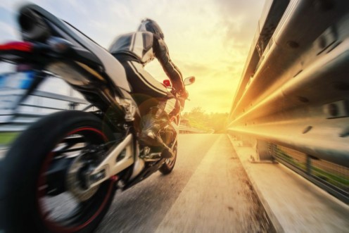 Afbeeldingen van Moto da strada sfreccia vicino al guard rail al tramonto