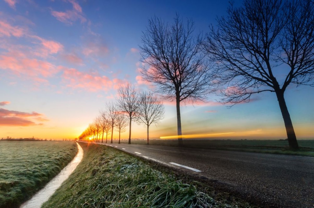 Image de A sunrise on a rural road cars passing by
