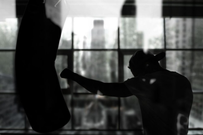 Boxer hits a punching bag against the window training photowallpaper Scandiwall