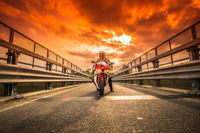 Afbeeldingen van Moto da strada pronta alla partenza sotto un cielo rosso al tramonto