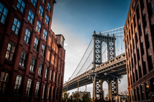 Image de Manhattan bridge seen from a narrow alley enclosed by two brick buildings on a sunny day in summer