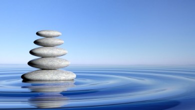 Bild på Zen stones stack from large to small  in water with circular waves and blue sky